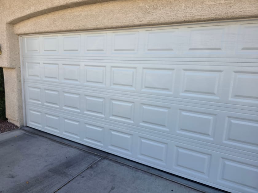 A white raised panel garage door, closed, photographed square on in daylight.