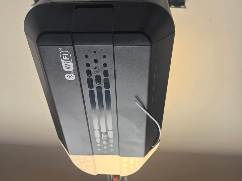 A ceiling mounted garage door opener head with its Wi-Fi indicator lights, seen from below.