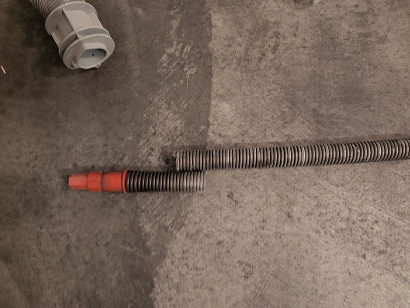 Close-up of a garage door torsion spring and its winding cone lying on a garage floor during a repair.