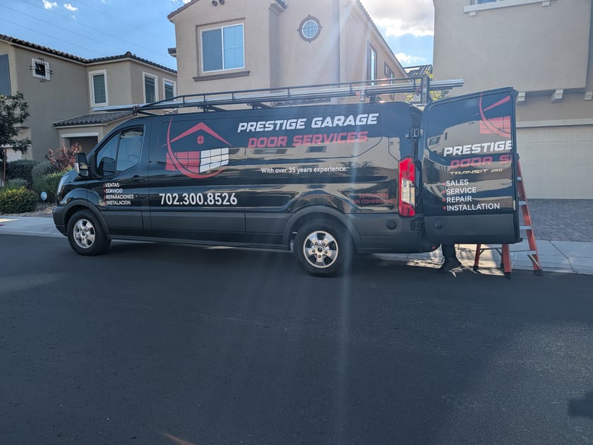 The Prestige Garage Door Services van, signwritten along its side, parked at the kerb on a residential street.